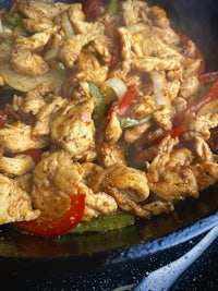 a skillet with chicken and peppers in it