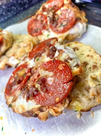 a pizza with pepperoni and cheese on top of a piece of parchment paper