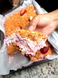 a person holding a piece of strawberry ice cream cake